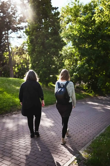 Zuzka a Tereza zezadu na procházce po cestě v parku.